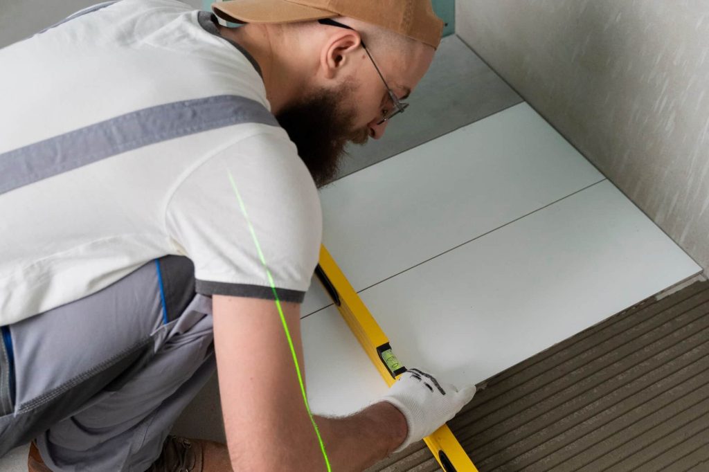 Installer aligning floor tiles using a level for accurate placement and perfect tile layout.