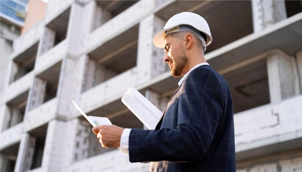 Engineer with blueprints at construction site.