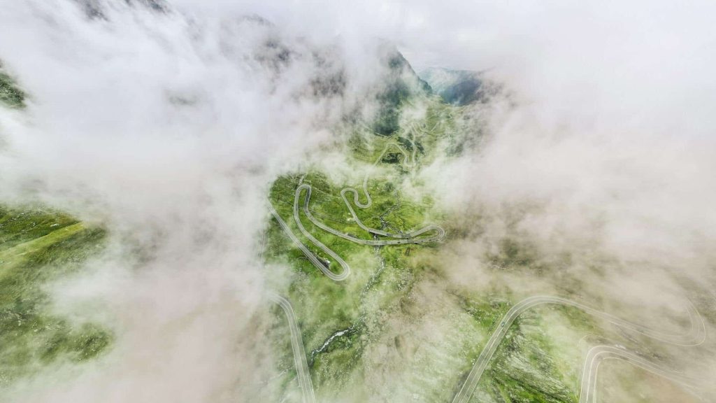 Aerial LiDAR scan of winding mountain roads, showcasing detailed terrain mapping and cloud-covered landscapes.