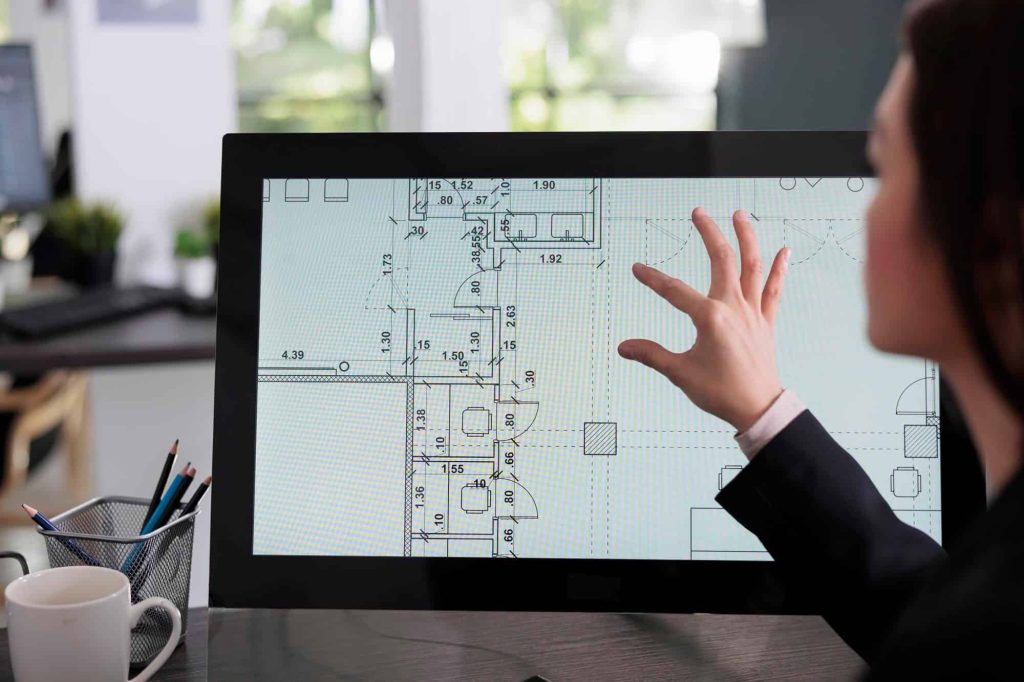 Architect reviewing detailed As-Built floor plans on a digital screen, emphasizing accurate documentation for healthcare facility renovations and compliance.